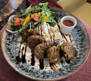 A restaurant meal with a salad and falafel and sauce