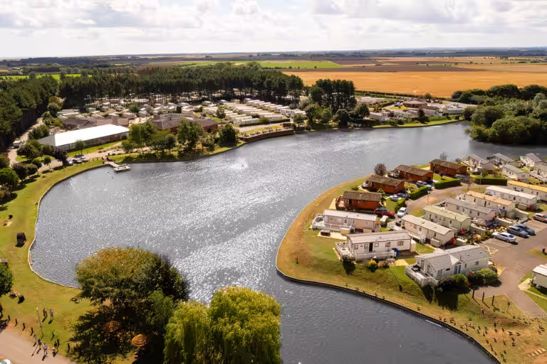 Lakeside Park holiday home park with fields, a lake and holiday homes taken from an aerial view