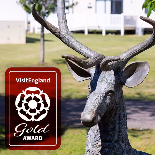 A metal statue of a deer and a visit England Gold award on top
