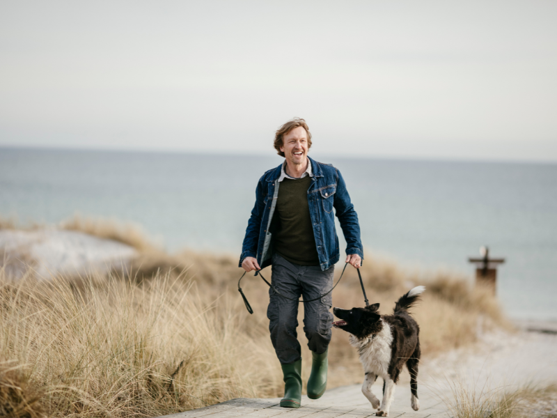 Best Dog Walks in Mablethorpe and Skegness: A Guide for Holiday Homeowners and Visitors 1 A man walking his dog on a beach in Skegness